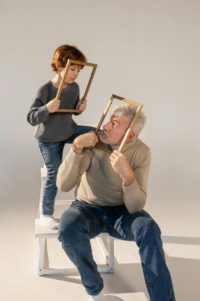 Dziadek i wnuk trzymają ramki, bawiąc się w jasnym studiu