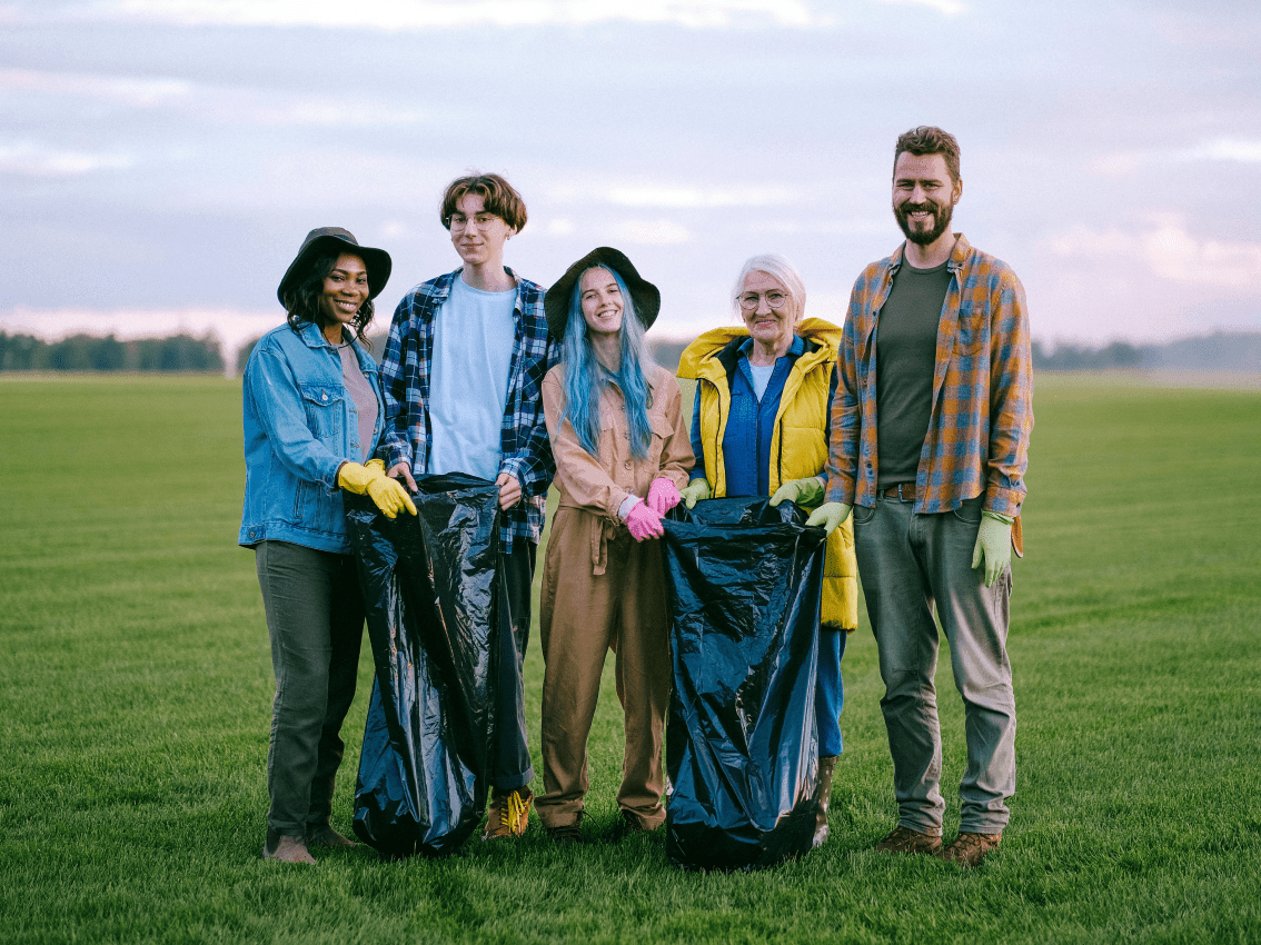 Grupa pięcu osób zbierających śmieci na świeżym powietrzu